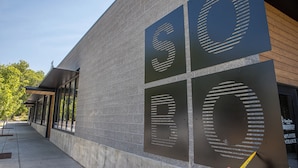 A building facade with large, dark metal panels featuring cut-out letters and numbers. - Modern condo in Downtown Bozeman w/private balcony, private parking, and AC - SOBO Urban Oasis (Bozeman)