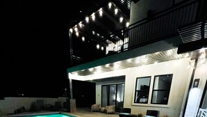 A swimming pool with a tiled deck, surrounded by outdoor seating and a covered area with string lights. - Ocotillo Springs 49| Private Heated Pool & Spa | 5 Bedroom & 5.5 Bath (SANTA CLARA)