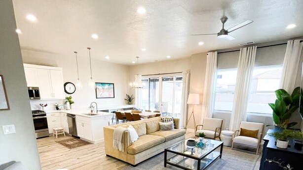 A spacious living area with a sofa, coffee table, and chairs. There is a kitchen in the background with cabinets and a microwave. - Ocotillo Springs 49| Private Heated Pool & Spa | 5 Bedroom & 5.5 Bath (SANTA CLARA)