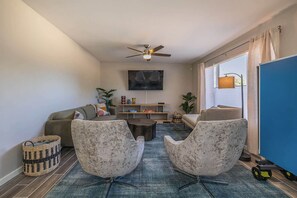 Una sala de estar moderna con un sofá, dos sillones, una mesa de centro y un televisor.