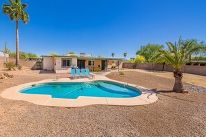 A residential property with a swimming pool, lounge chairs, and a patio area.