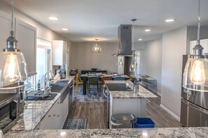 Una cocina moderna con encimeras de granito, electrodomésticos de acero inoxidable e iluminación colgante.