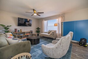 A living room with a sofa, armchair, coffee table, and a TV mounted on the wall.