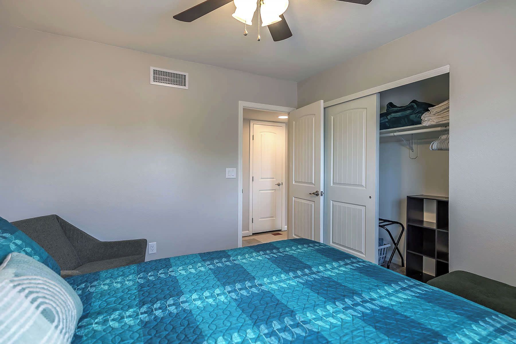 A bedroom with a bed, a closet, and a ceiling fan.