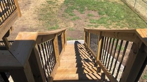 A wooden staircase with railings leading to a grassy area.