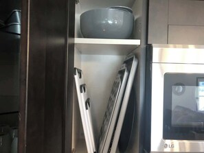 Une cuisine équipée d’un réfrigérateur en acier inoxydable, d’un four à micro-ondes et d’une étagère sur laquelle se trouvent un bol et une spatule.