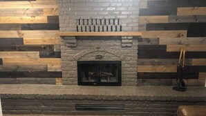 A fireplace with a stone surround, set in a room with wooden panel walls.