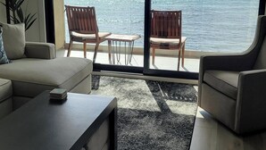 Ein modernes Wohnzimmer mit einem großen Schiebeglasfenster, das auf einen Balkon mit Meerblick führt.