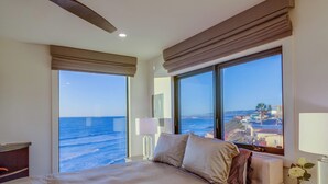 Ein Hotelzimmer mit Bett, Nachttisch, Lampe und Meerblick.
