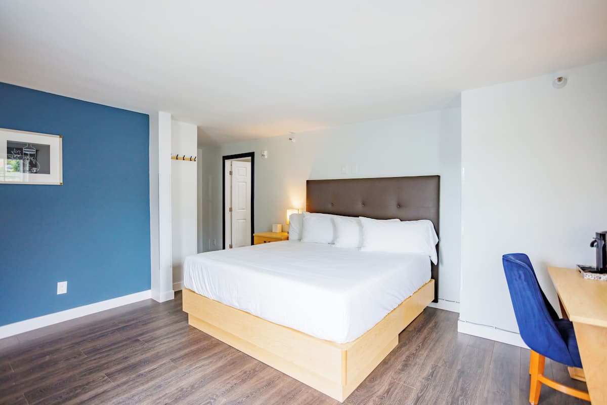 A modern hotel room with a large bed, a desk, and a chair.