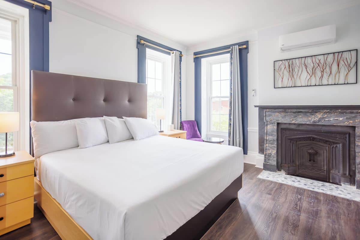 A spacious bedroom with a large bed, a fireplace, and a view of the outdoors.