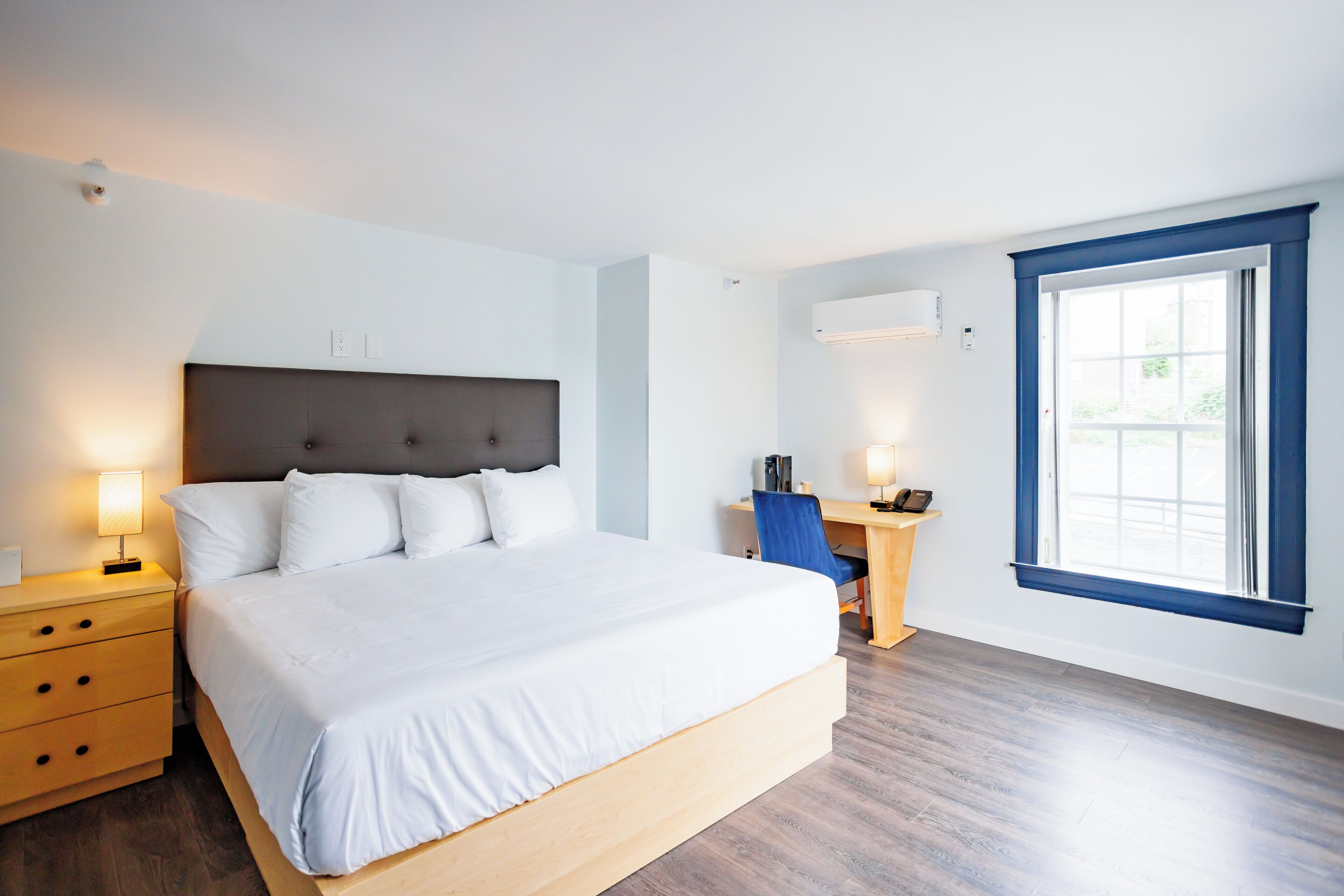 A modern bedroom with a large bed, bedside tables, a desk, and a window with curtains.