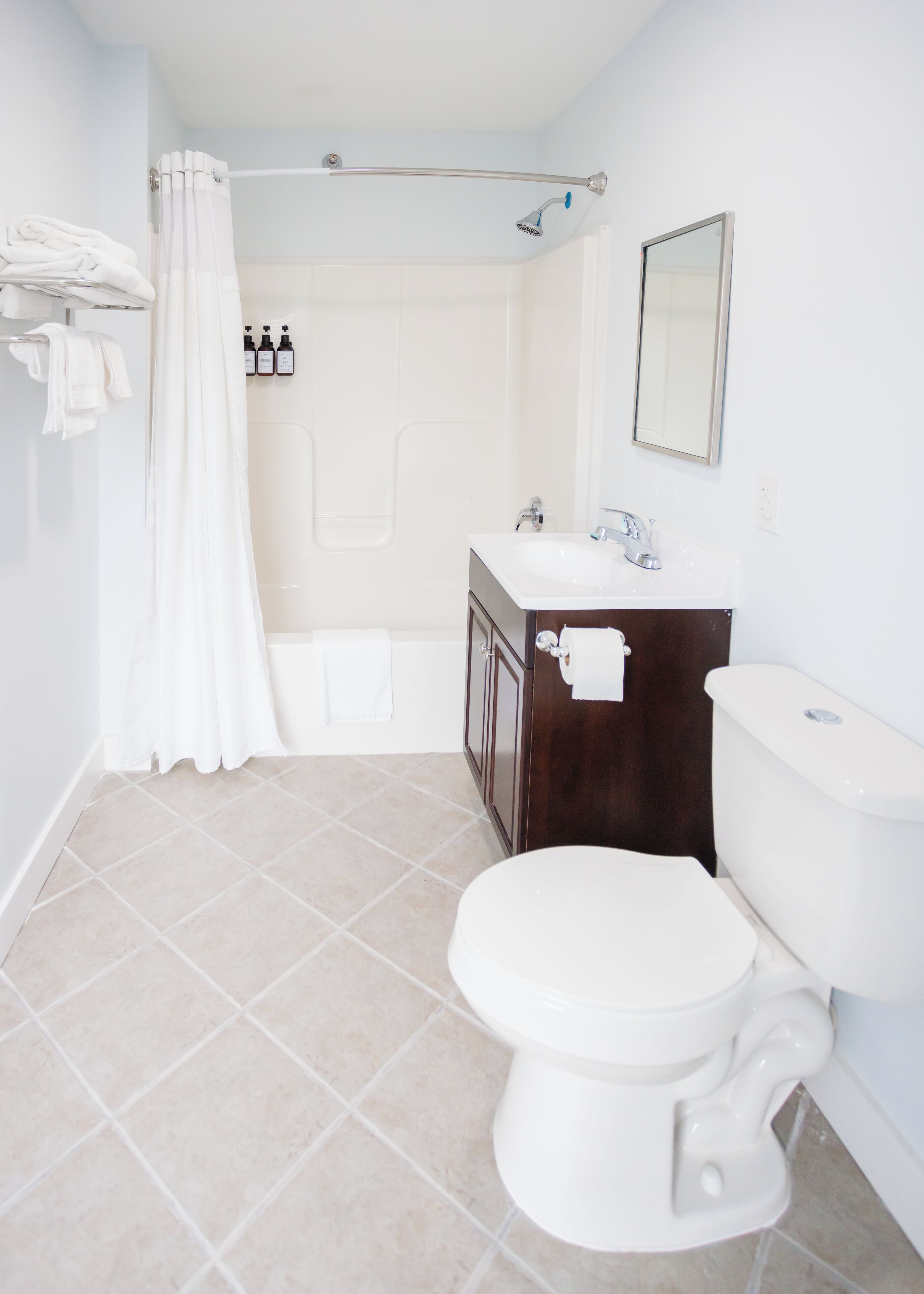 A bathroom with a toilet, sink, and shower. There are towels and toiletries visible.