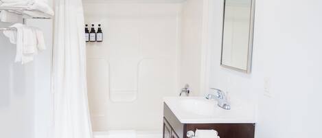 A bathroom with a toilet, sink, and shower. There are towels and toiletries visible.