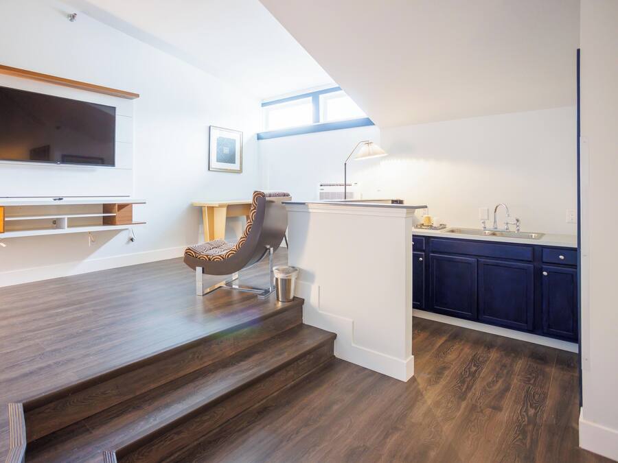 A modern kitchen with dark wooden flooring, a built-in island, and a dining area with a chair and a TV.