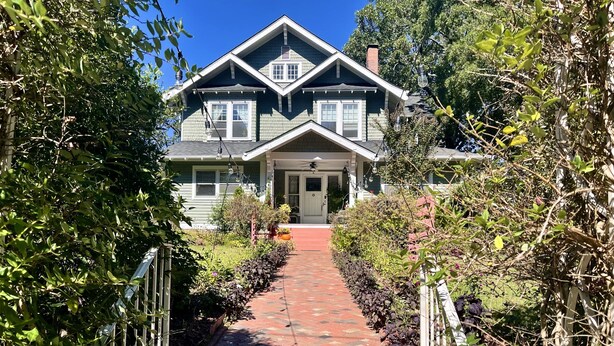 A house with a brick pathway leading to the front door, surrounded by greenery. - Greenwood Bed & Breakfast (Greensboro)