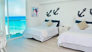 A hotel room with two beds, a large window with a view of the ocean, and nautical-themed wall decor. - Ocean view studio, great views, balcony, beach, pool, gym, jacuzzi (Cancún)