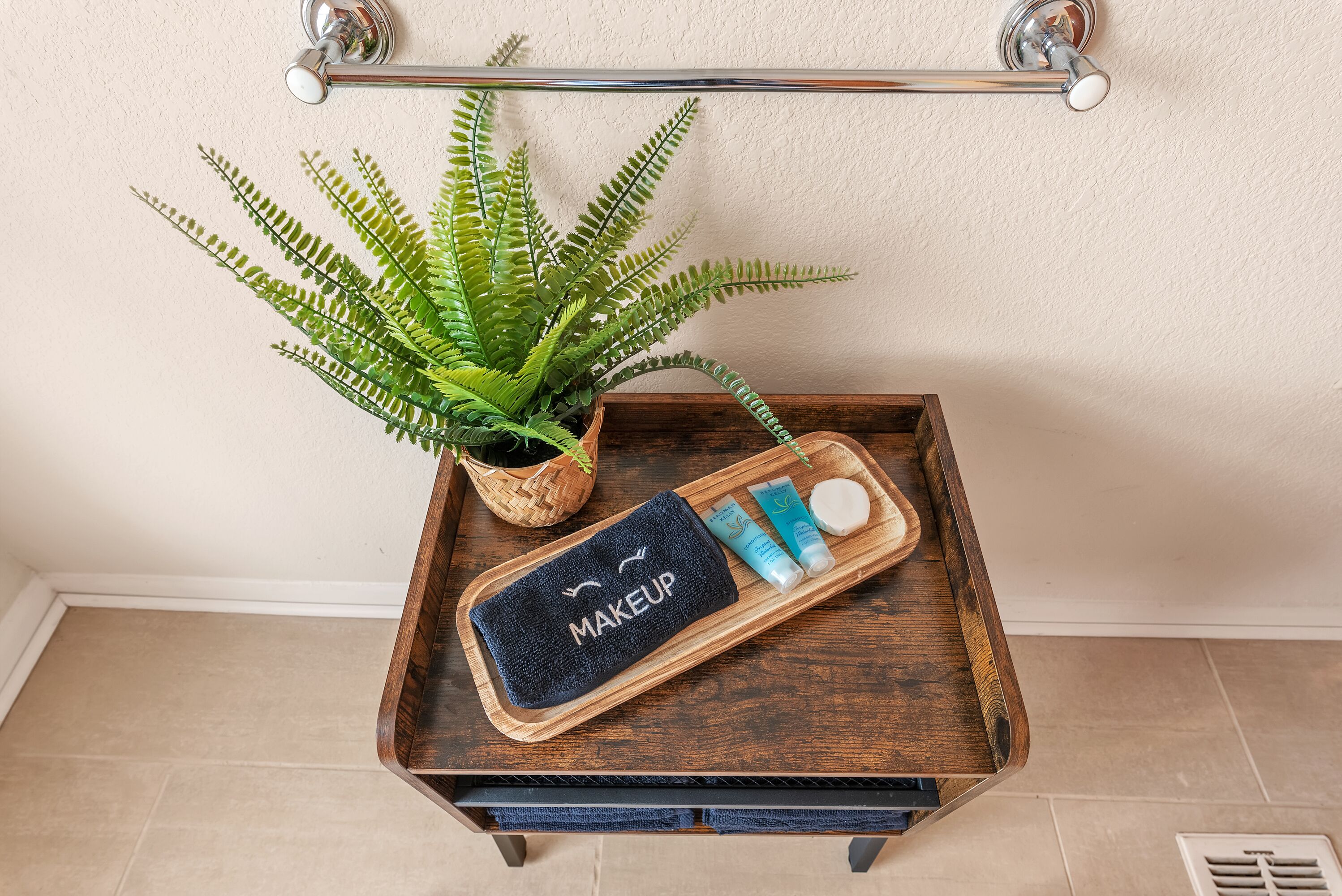 A wooden tray with a makeup towel, a potted fern, and skincare products.