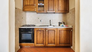 A kitchen with wooden cabinets, a stove, and a sink. - Inferno Double - One Bedroom Apartment, Sleeps 2 (Firenze)