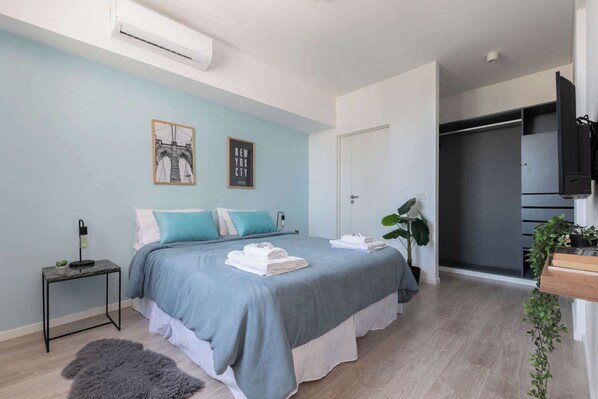 Ein modernes Schlafzimmer mit Bett, Nachttisch und großem Fenster.