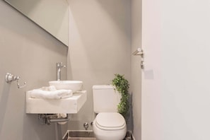A compact bathroom with a white sink, toilet, and a small plant.