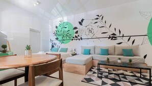 Una sala moderna con una mesa de comedor de madera, un sofá con cojines color turquesa y una alfombra con estampado geométrico.