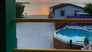 A view of a beach at sunset with a pool and a house in the foreground. - Waterfront 2 Bedroom/ 2 bath POOL home w/ Stunning Ocean Views!! (Caye Caulker Village)