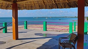 A beachside patio with a thatched roof, a concrete floor, and a view of the sea with boats. - Waterfront 2 Bedroom/ 2 bath POOL home w/ Stunning Ocean Views!! (Caye Caulker Village)