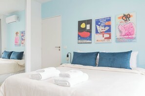 A hotel room with a bed, two pillows, a wall-mounted air conditioner, and three posters on the wall. - MOT Rentals + Araoz 'D' - 1 Bd in Palermo Soho (Palermo)
