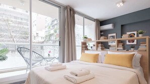 Ein modernes Hotelzimmer mit einem großen Bett, einem Balkon mit Stuhl und Blick auf die Stadt.