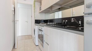 A compact kitchen with a washing machine, oven, and a double sink.