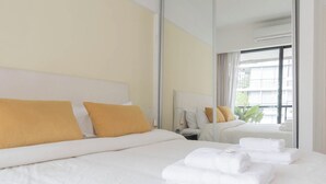Une chambre d’hôtel avec un grand lit, du linge de lit blanc et un miroir qui reflète la pièce.