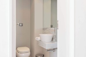 Une salle de bain moderne avec des toilettes blanches, un lavabo en marbre et un grand miroir.