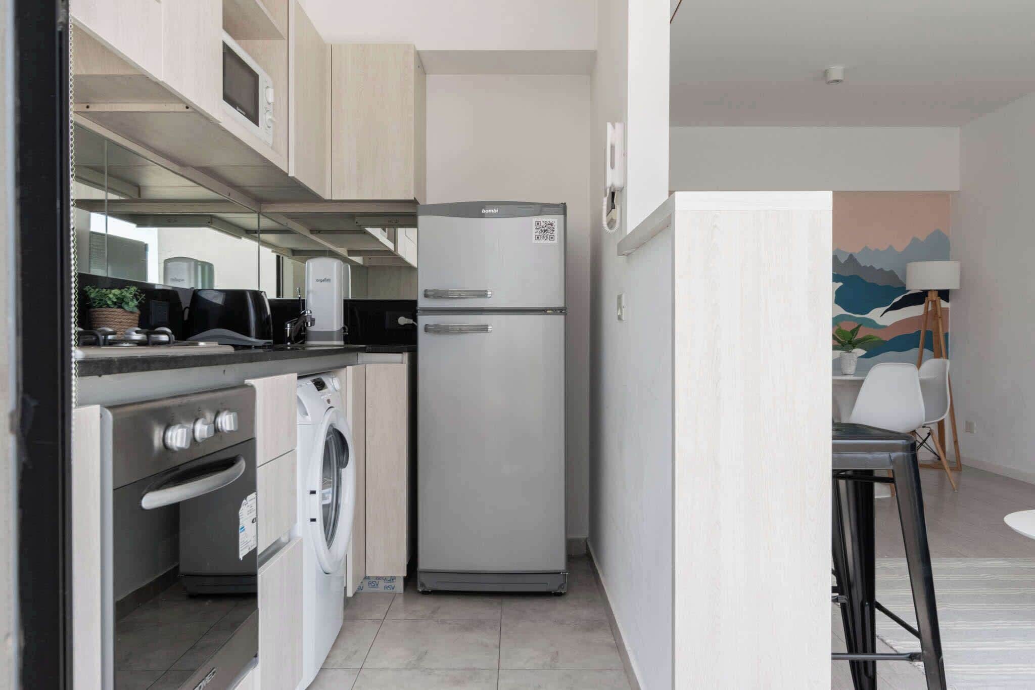 Cocina compacta con refrigerador, horno y lavadora.