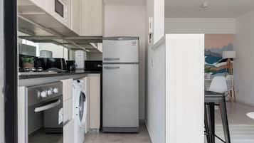 Cocina compacta con refrigerador, horno y lavadora.