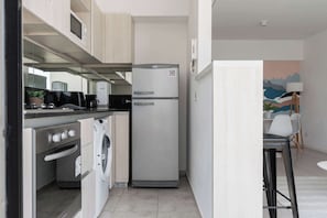 A compact kitchen with a refrigerator, oven, and washing machine.