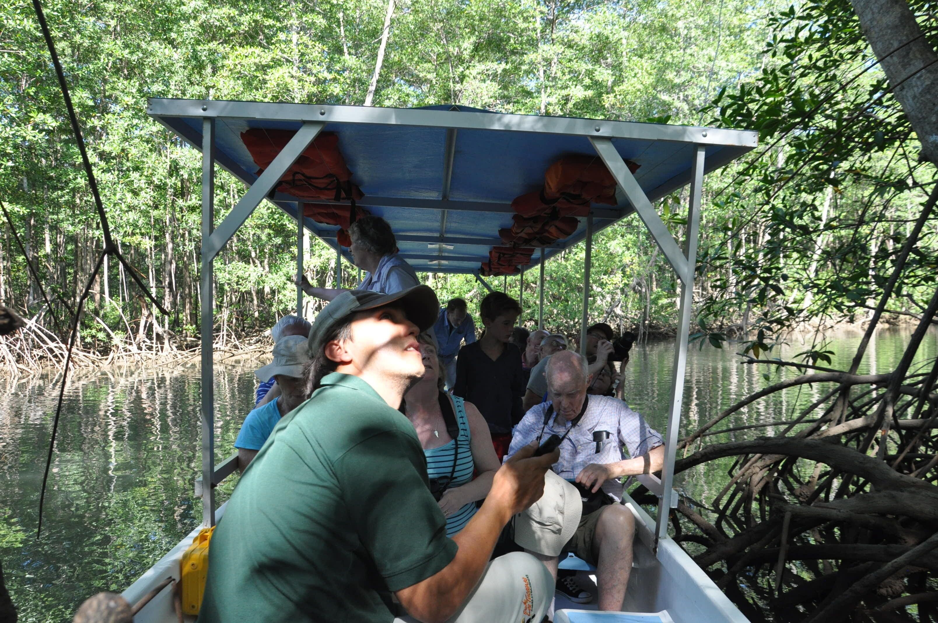 A boat with a metal roof and life jackets hanging on the sides, surrounded by water and trees.