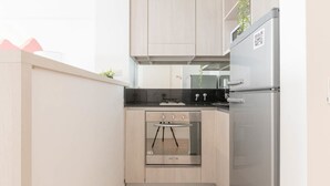 A compact kitchen with a built-in oven, a refrigerator, and light wooden cabinets. - MOT Rentals + Zapiola 2300 'D' - Loft Belgrano (Belgrano)
