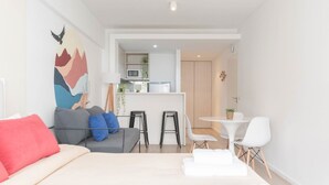 A modern hotel room with a bed, a sofa, a dining area, and a kitchen in the background. - MOT Rentals + Zapiola 2300 'D' - Loft Belgrano (Belgrano)