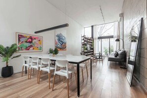 A modern living room with a large window, a sofa, a coffee table, and a bookshelf.
