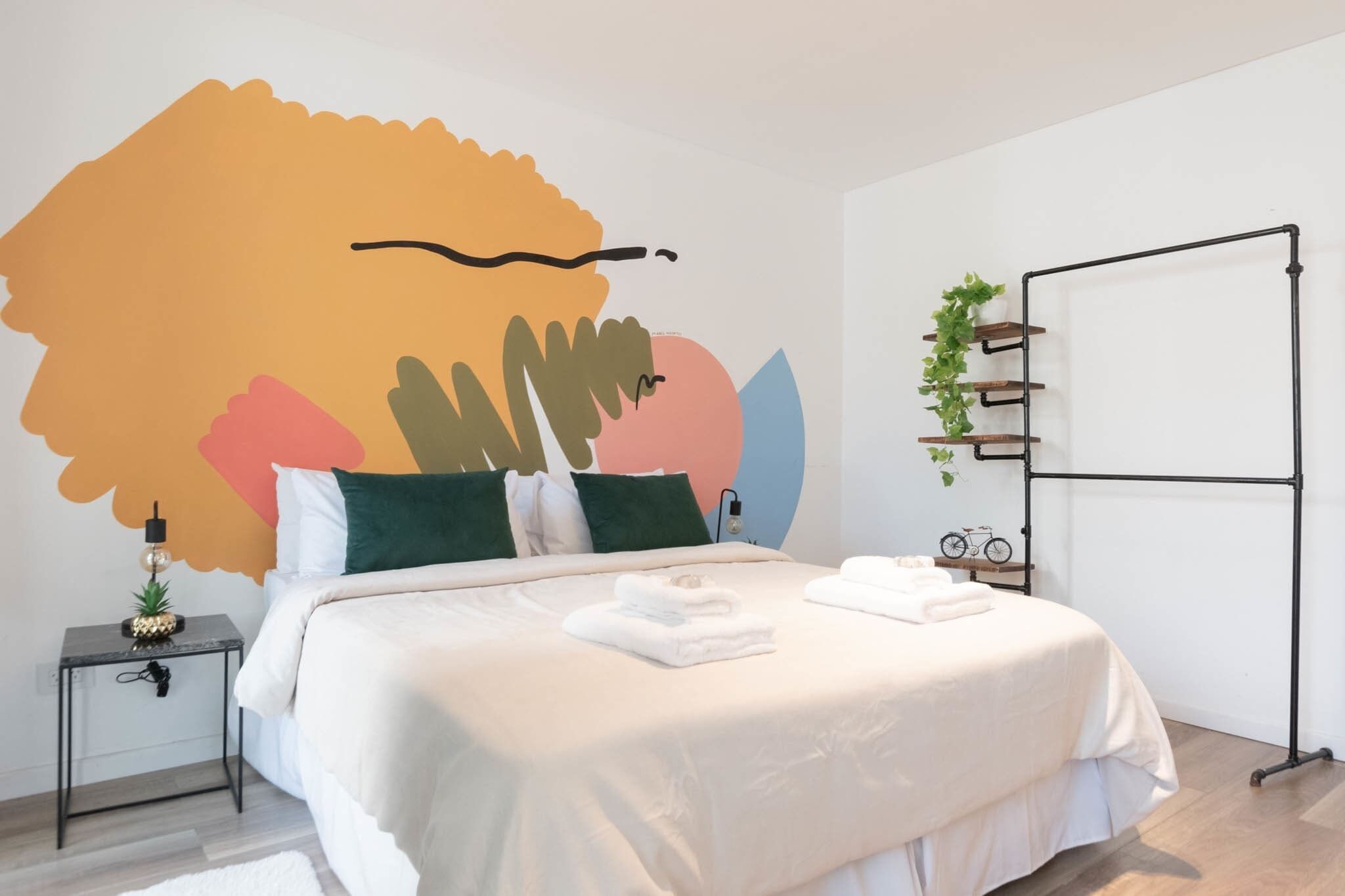Una camera da letto moderna con un letto grande, una mensola a parete con piante e un piccolo tavolo con una lampada.
