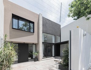 Ein modernes, zweistöckiges Haus mit flachem Dach, großen Fenstern und einer Betonfassade.