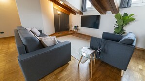 Una sala de estar moderna con un sofá gris, una mesa de centro de vidrio y una planta grande.