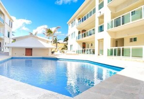 A swimming pool surrounded by a building with balconies and a clear blue sky. - Cancun Beach 3 Brms apartment, great area, stunning beach (Cancún)