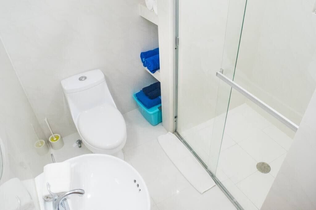 A modern bathroom with a toilet, sink, and glass shower enclosure.