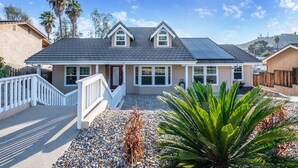 A two-story house with a sloped roof, a front porch, and a driveway. - The Ultimate Family Getaway- Game Room/Pool/Hot Tub/Human Chess! (Escondido)