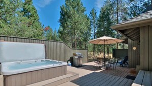 Un bain à remous sur une terrasse en bois, avec un barbecue et du mobilier d’extérieur.
