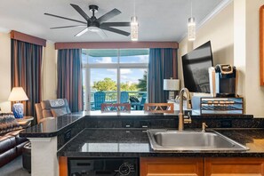 A modern kitchen with a built-in dishwasher, a large sink, and a ceiling fan.