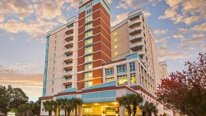 A multi-story hotel with a modern design, featuring a prominent entrance and balconies on each floor.
