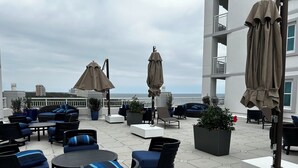 A rooftop terrace with outdoor seating, umbrellas, and potted plants.